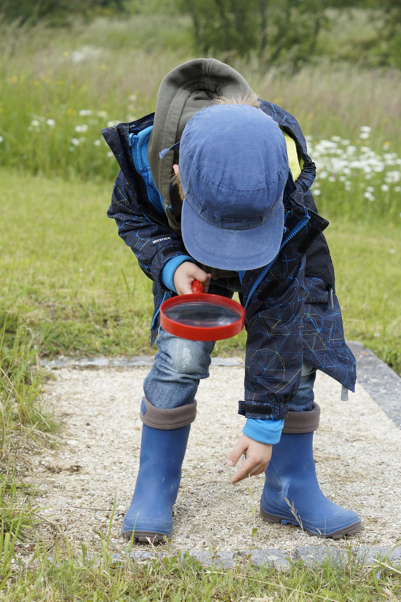 A child exploring the outdoors with a magnifying glass.